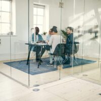 Smiling businesspeople meeting together inside of a glass office